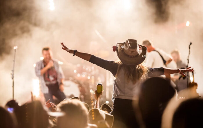 Person in cowboy hat cheering at concert at Thunder Ridge Nature Arena