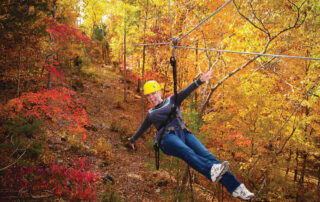 Person ziplining through Ozark fall foliage, one of the top Branson outdoor activities